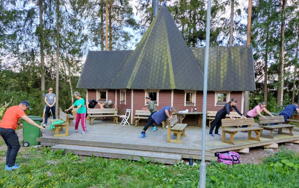 Ihmisiä jumppaamassa kodan edessä.